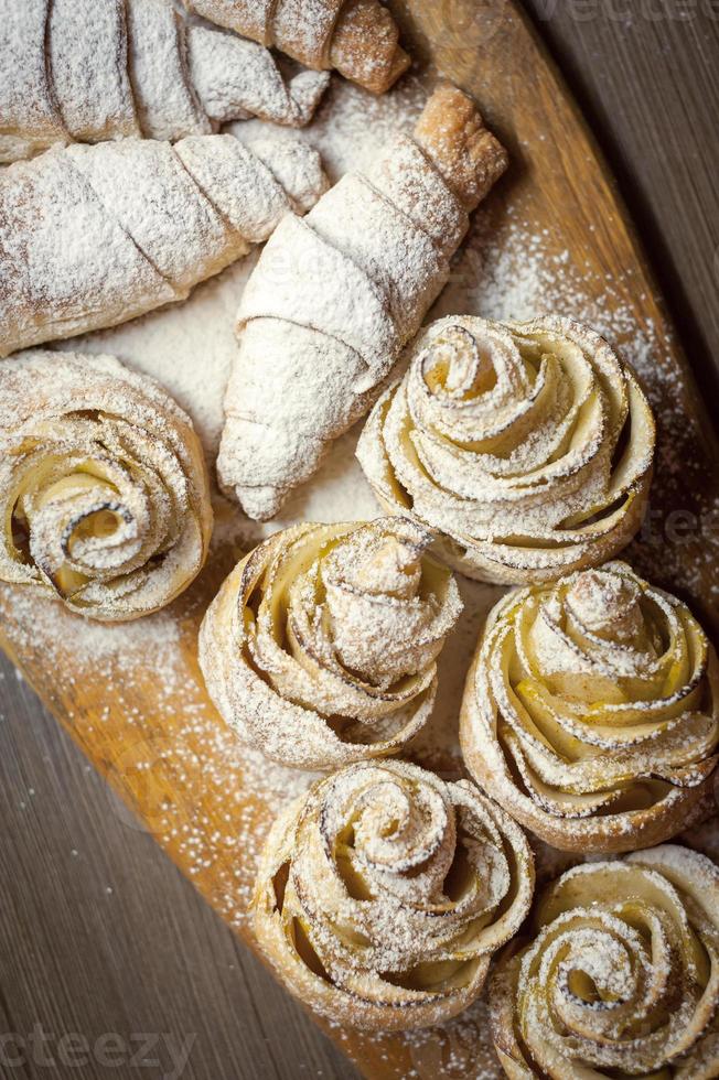 Close up of delicious croissants and pastries with apples, on a wooden Board in a cafe photo