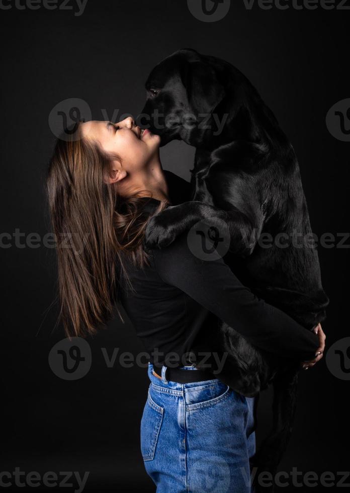 A girl holds a Labrador Retriever dog in her arms. photo