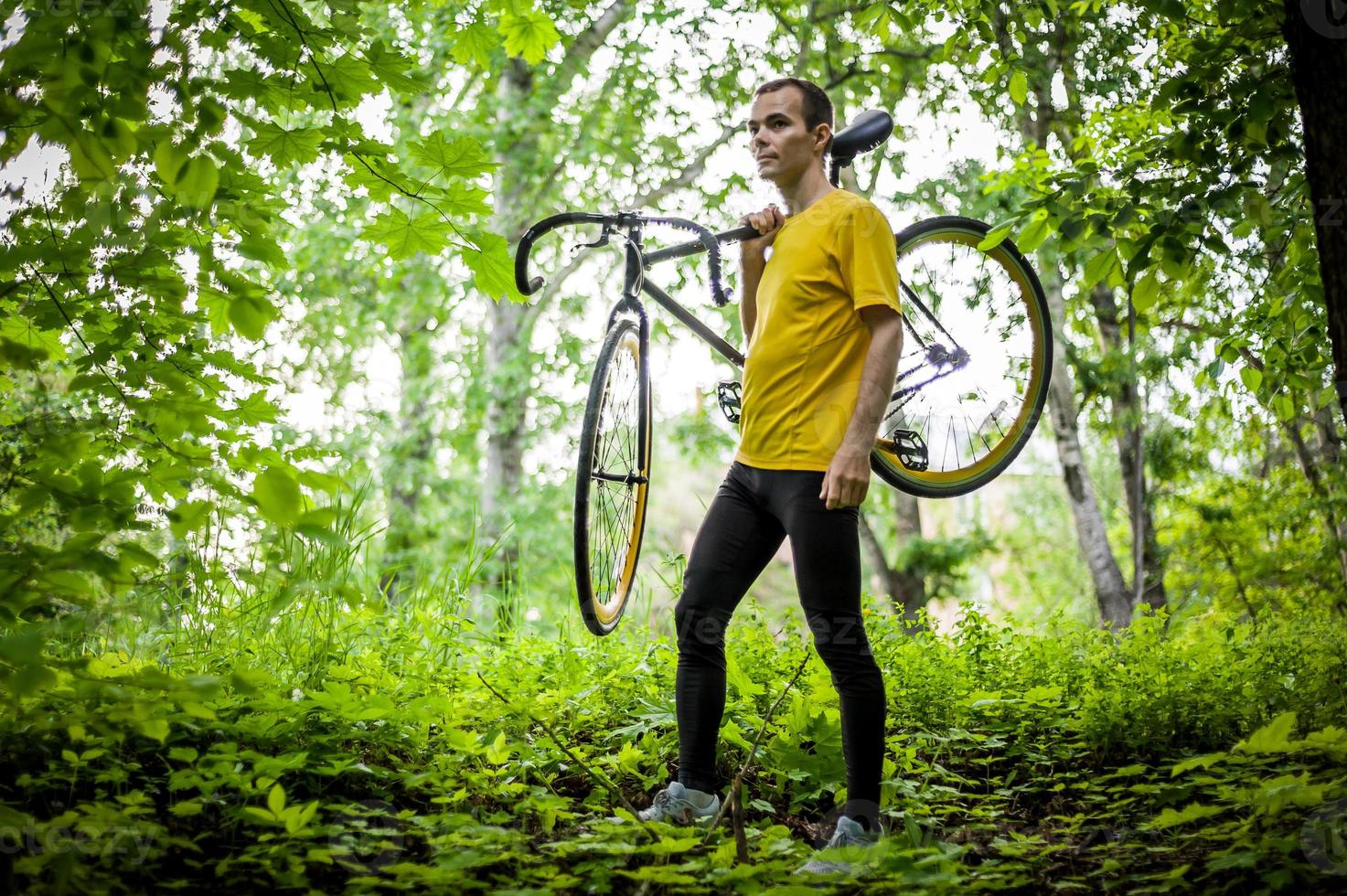 A young Man stopped to rest With his Bicycle in a public Park. photo