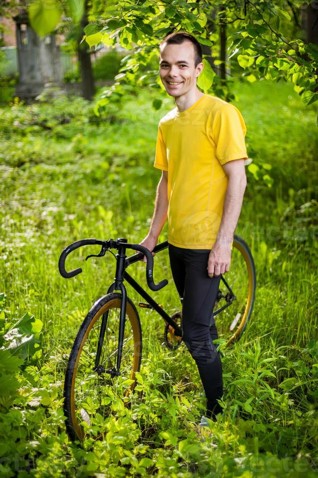 A young Man stopped to rest With his Bicycle in a public Park. photo