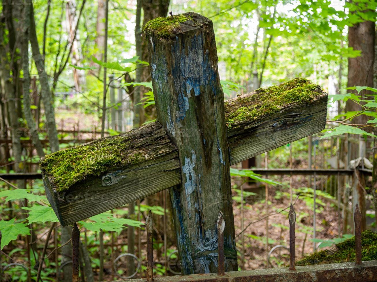 An old unattended cross covered with green moss. photo