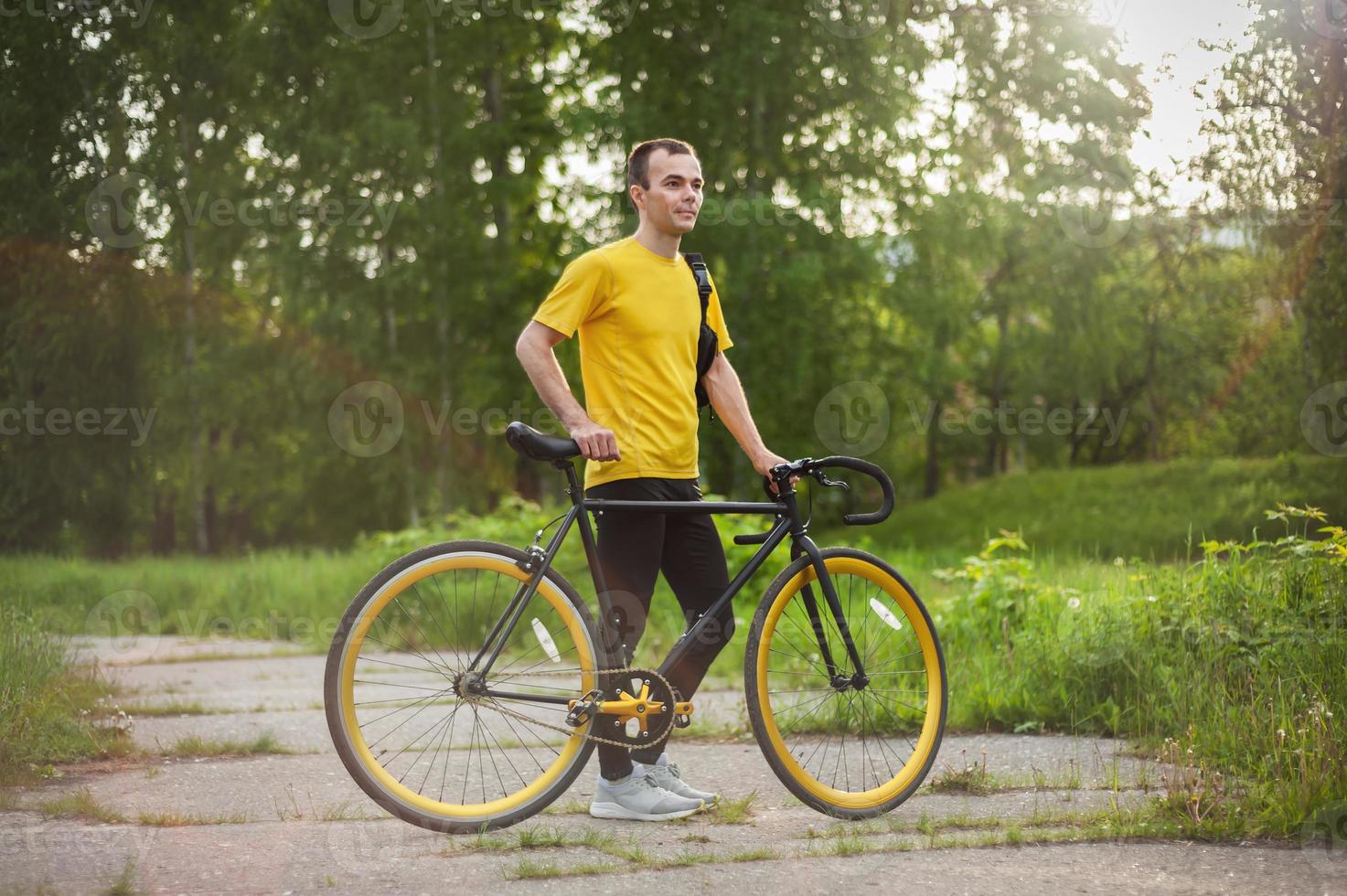 A young Man stopped to rest With his Bicycle in a public Park. photo