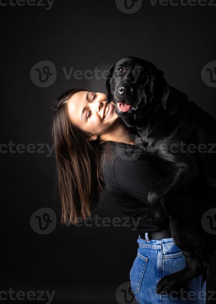 A girl holds a Labrador Retriever dog in her arms. photo