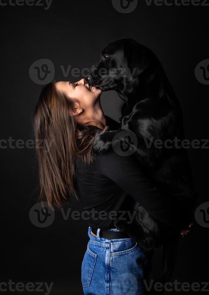 A girl holds a Labrador Retriever dog in her arms. photo