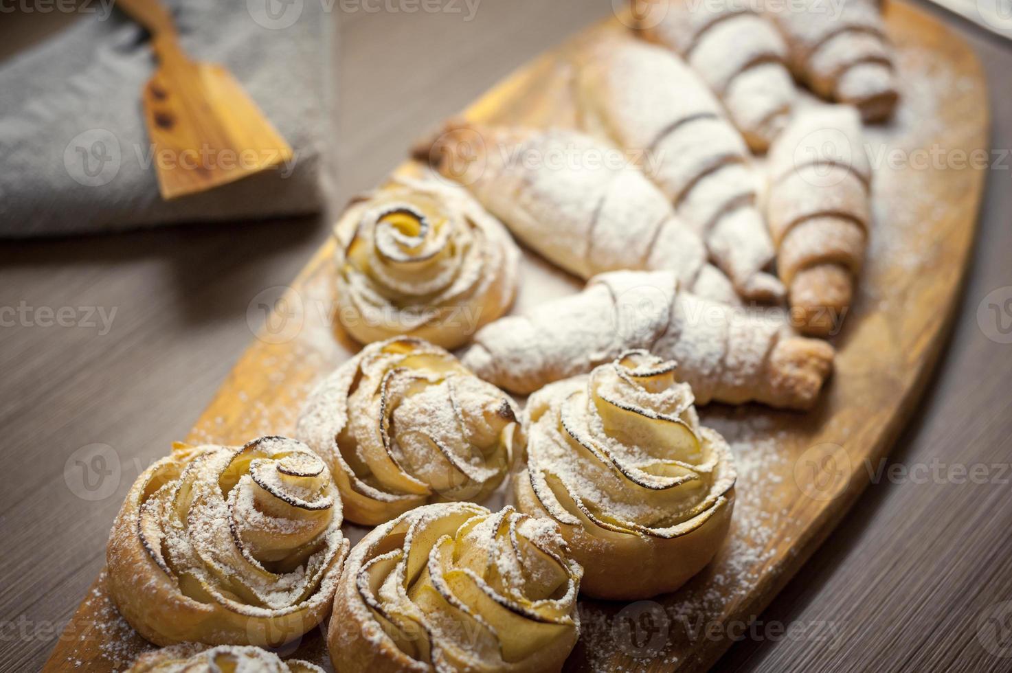 Close up of delicious croissants and pastries with apples, on a wooden Board in a cafe photo