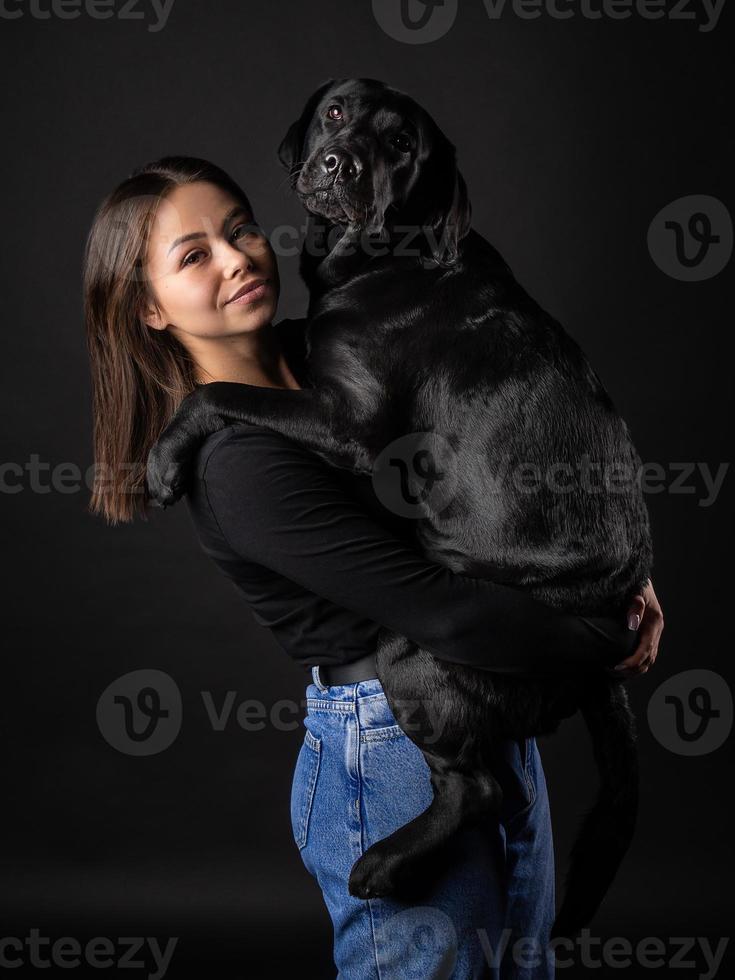 A girl holds a Labrador Retriever dog in her arms. photo
