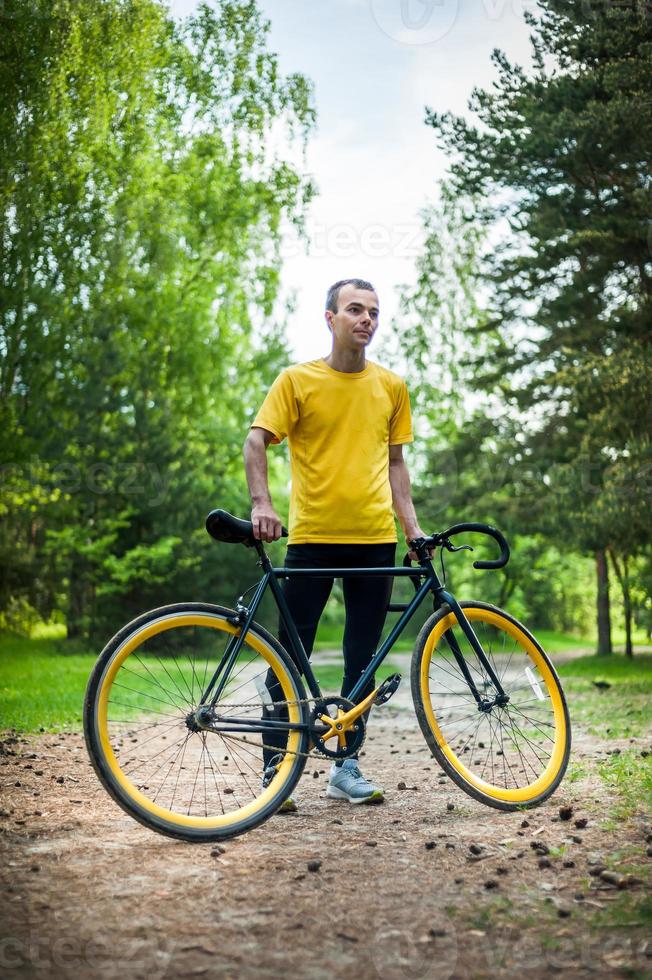 A young Man stopped to rest With his Bicycle in a public Park. photo