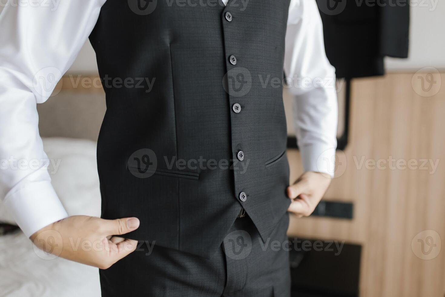 Close up preparation pose of a man fixing and holding the bottom of his black tuxedo and white shirt. photo