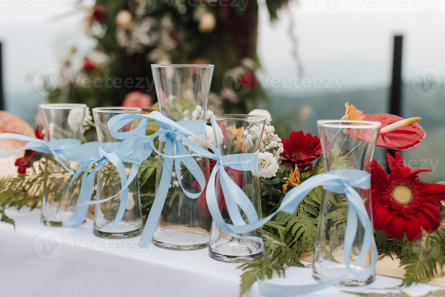 hermosa boda al aire libre con tema rústico o cena romántica, configuración de altar blanco, jarrones de ceremonia de arena de boda con vidrio alineado con decoración de flores naturales. foto