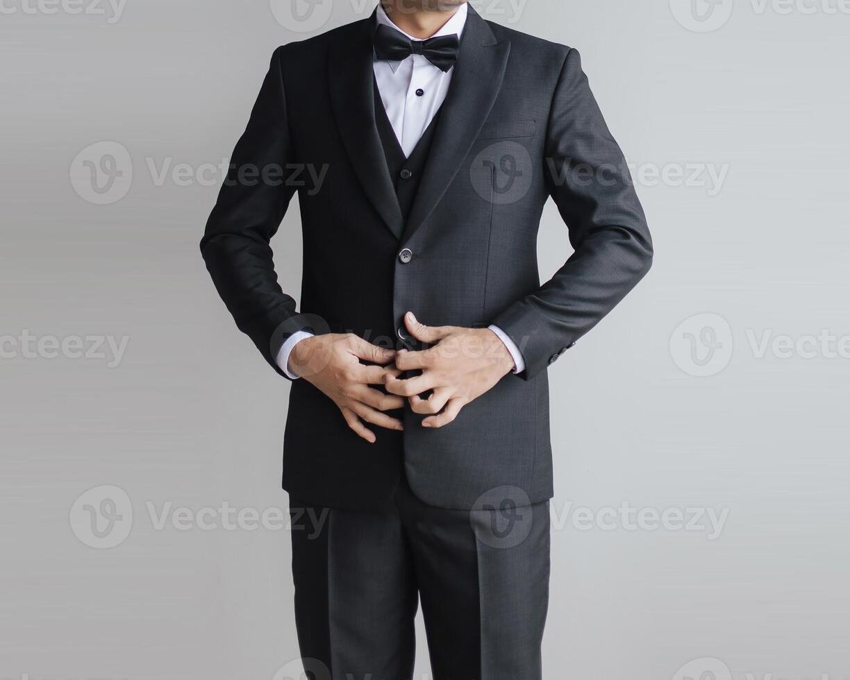 Detail half body close up a man black suit with vest inside with bow tie and white shirt opening the suit or fixing it by holding the suit button. photo