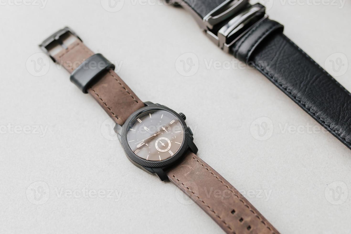 Presentation of detail brown casual hand watch and black formal belt with empty space for marketing material. photo