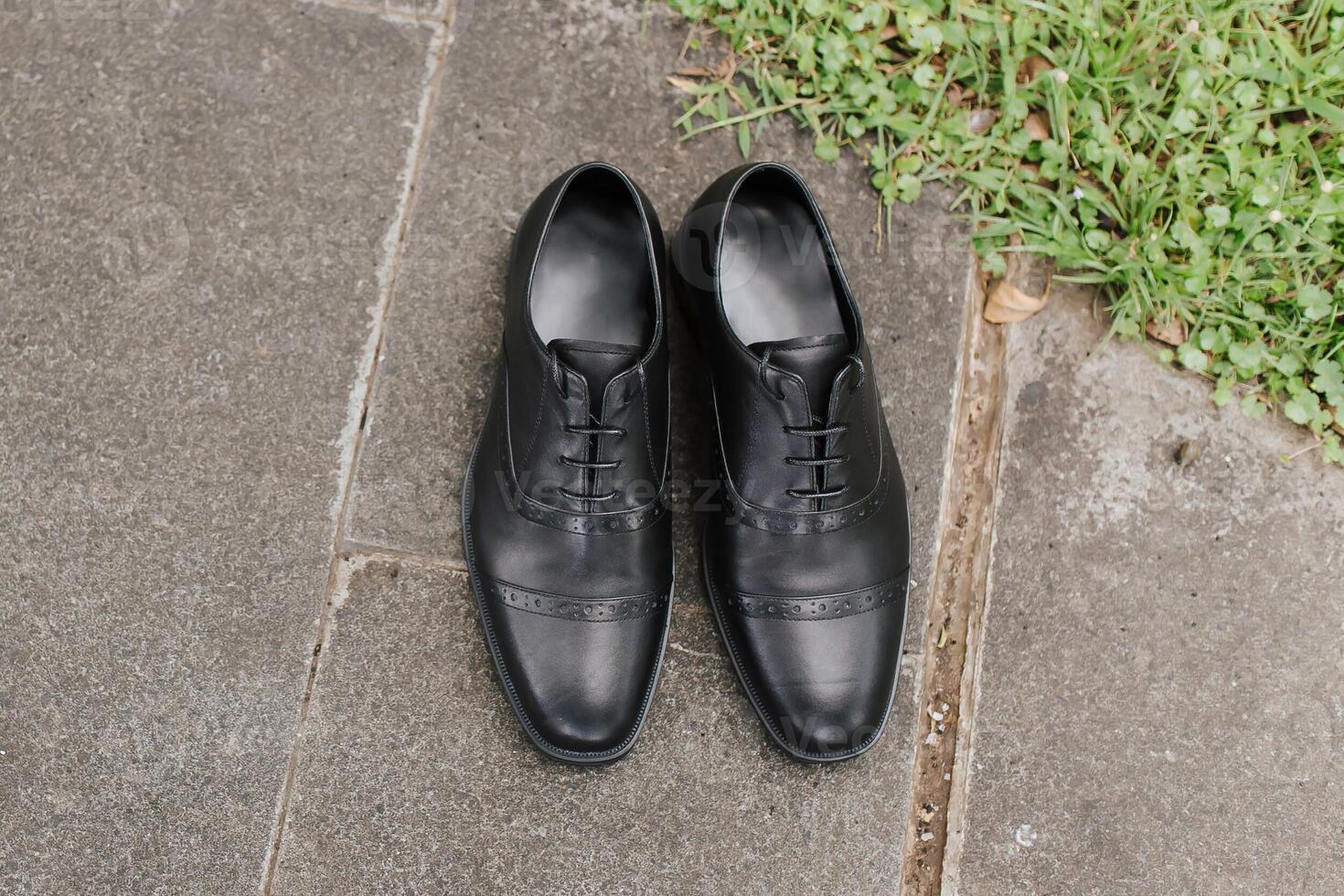 A pair of formal black gentlemen shoes laying on the ground, with negative space good for concept print. photo