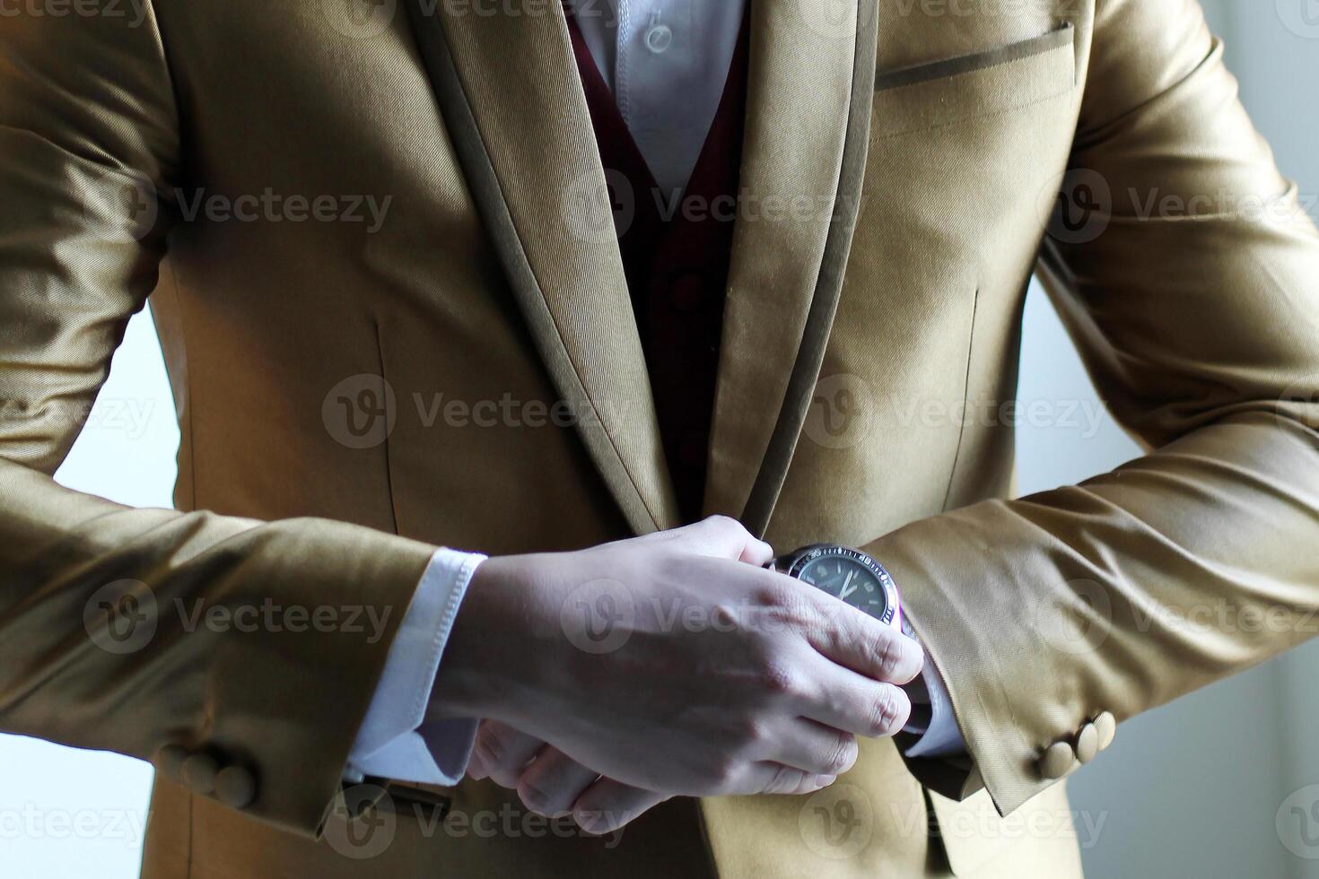 A man with golden suite holding his watch or fixing it. photo