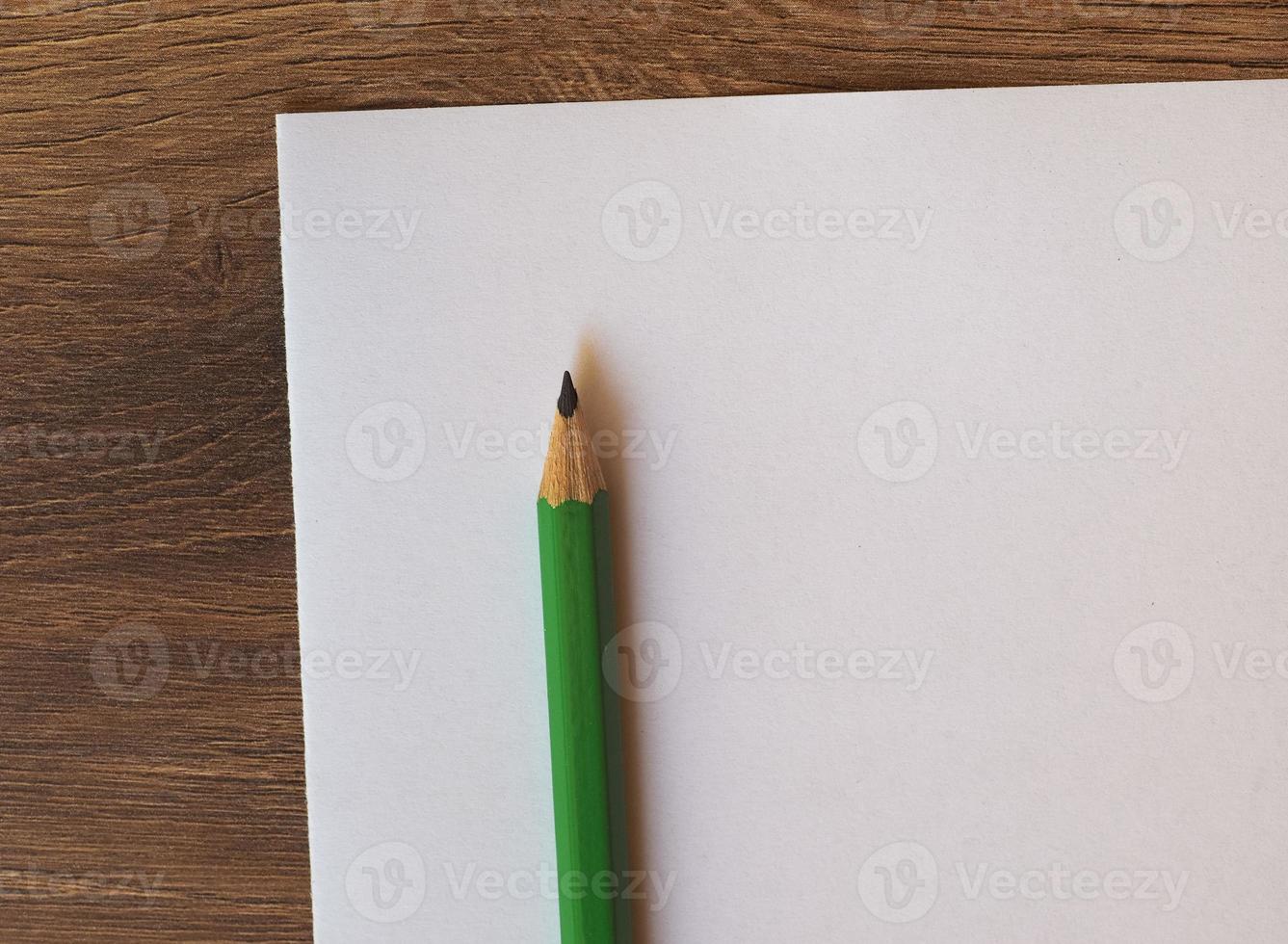 lápiz verde en el escritorio de la hoja de papel foto