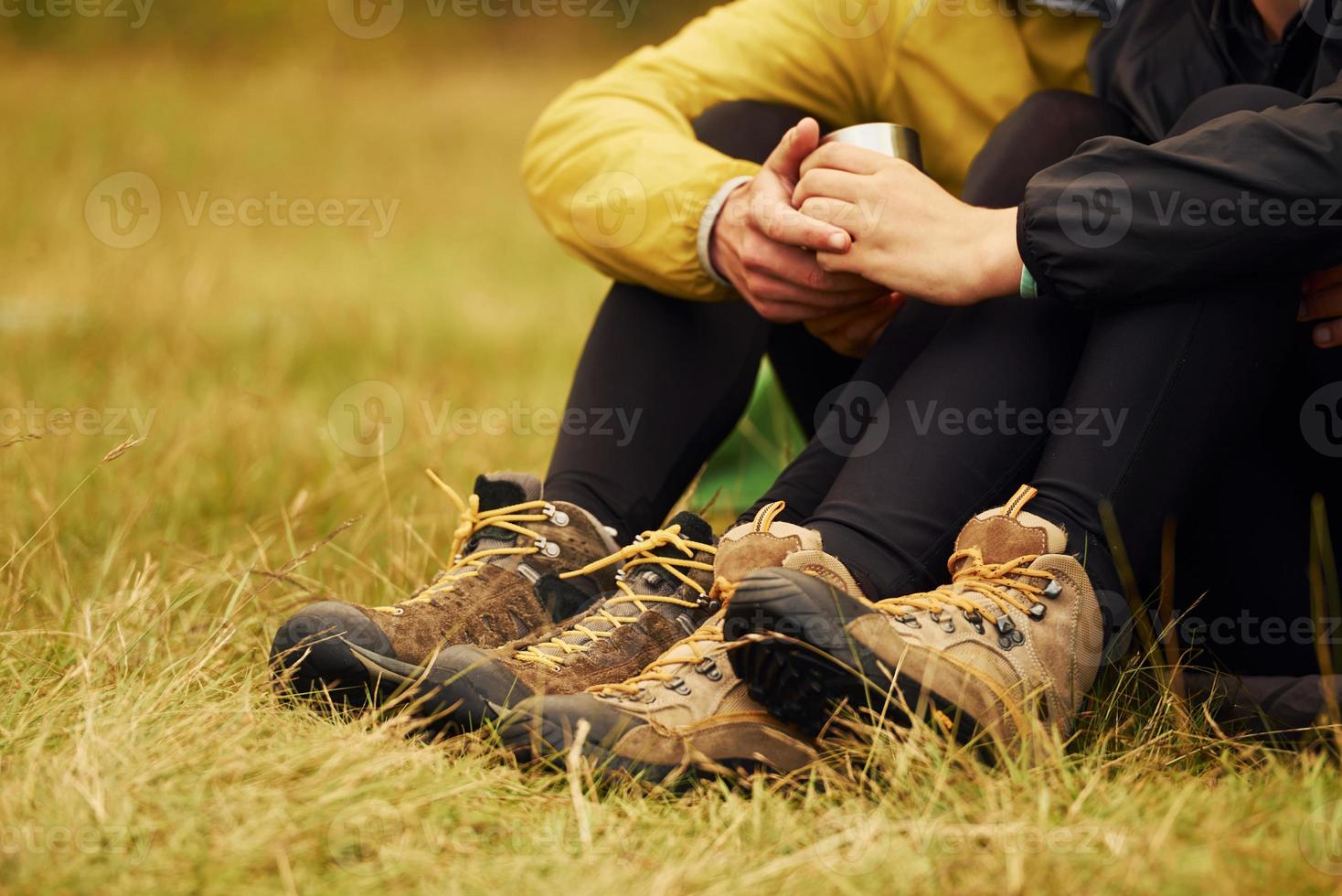 Particle close up view of couple that sitting near theirs tent and holding metallic cup with drink photo