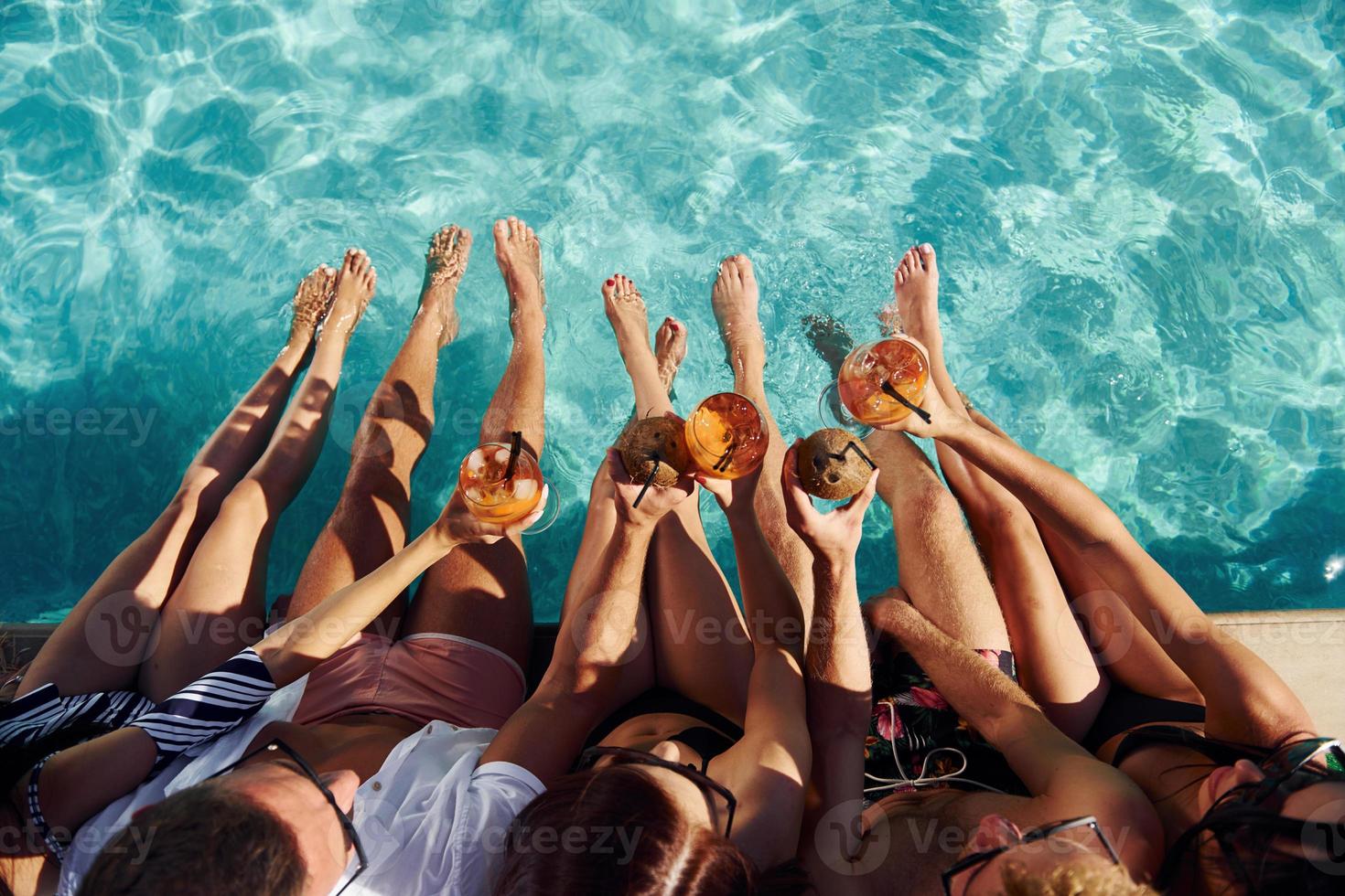 vista superior del grupo de jóvenes felices que se divierten en la piscina durante el día foto