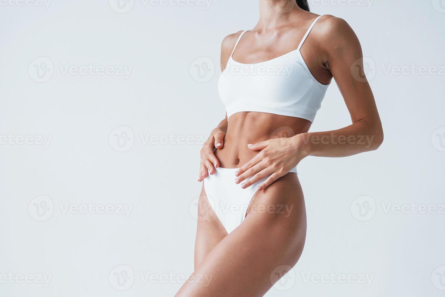 Shows white underwear. Beautiful woman with slim body is in the studio photo