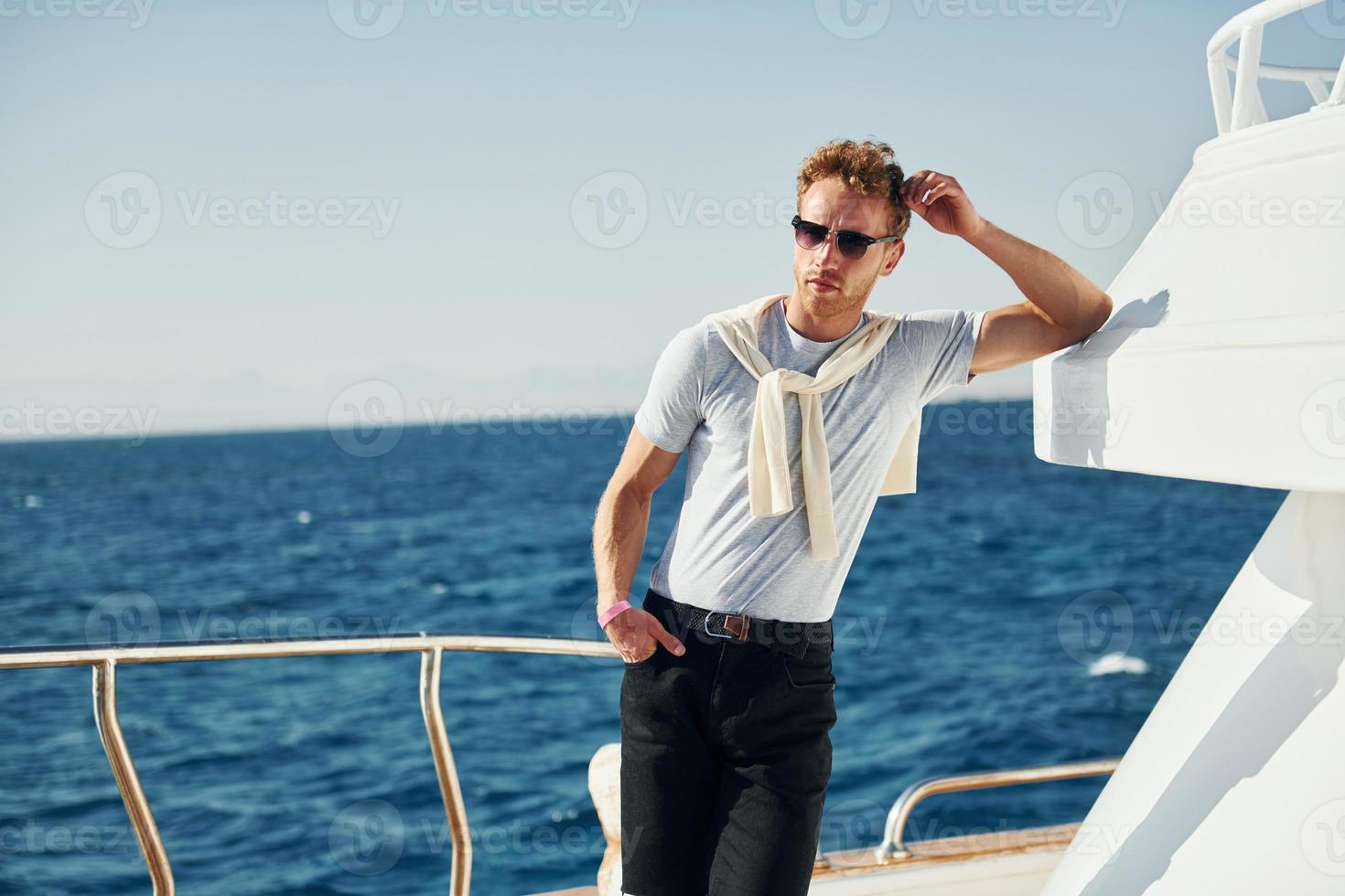 Posing for a camera. Young male tourist is on the yacht on the sea. Conception of vacation photo