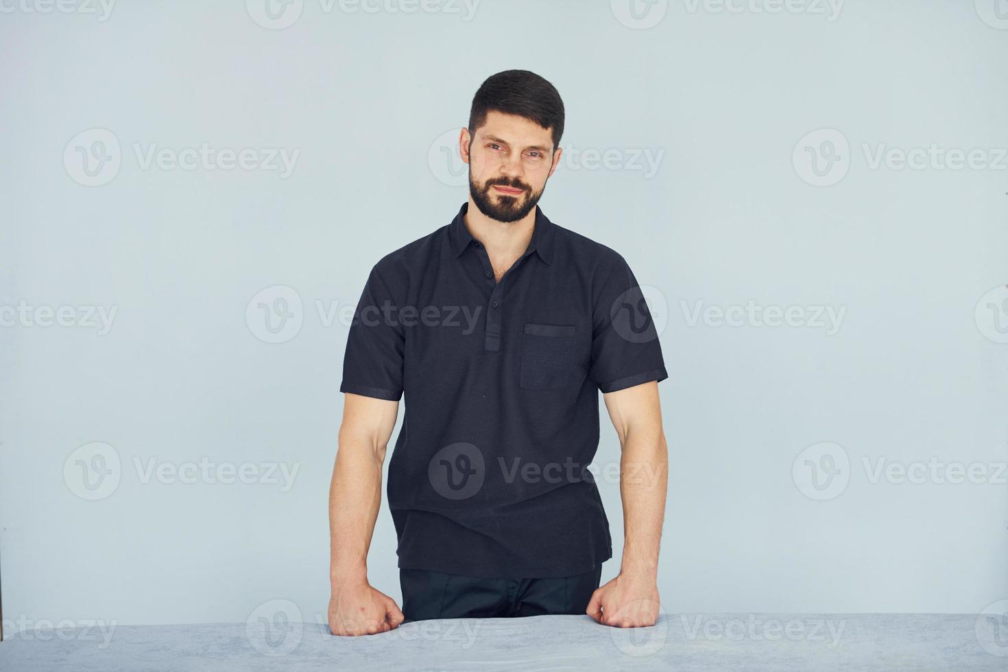 hombre serio en camisa de pie en el interior contra el fondo blanco foto