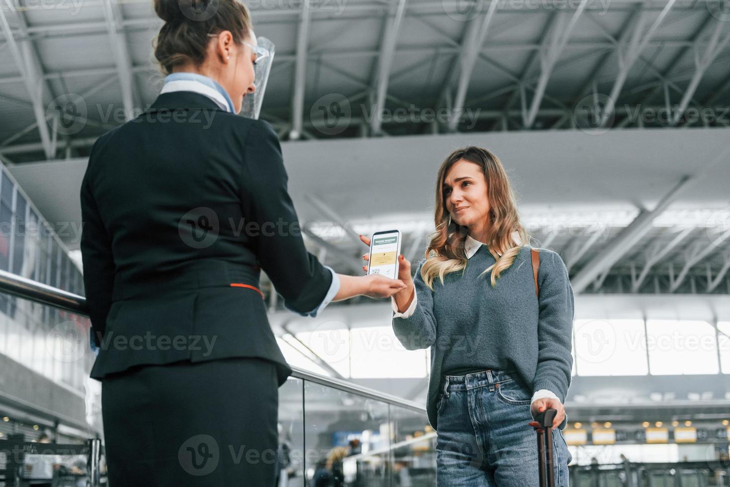 Vaccination certificate in the phone. Young female tourist is in the airport at daytime photo