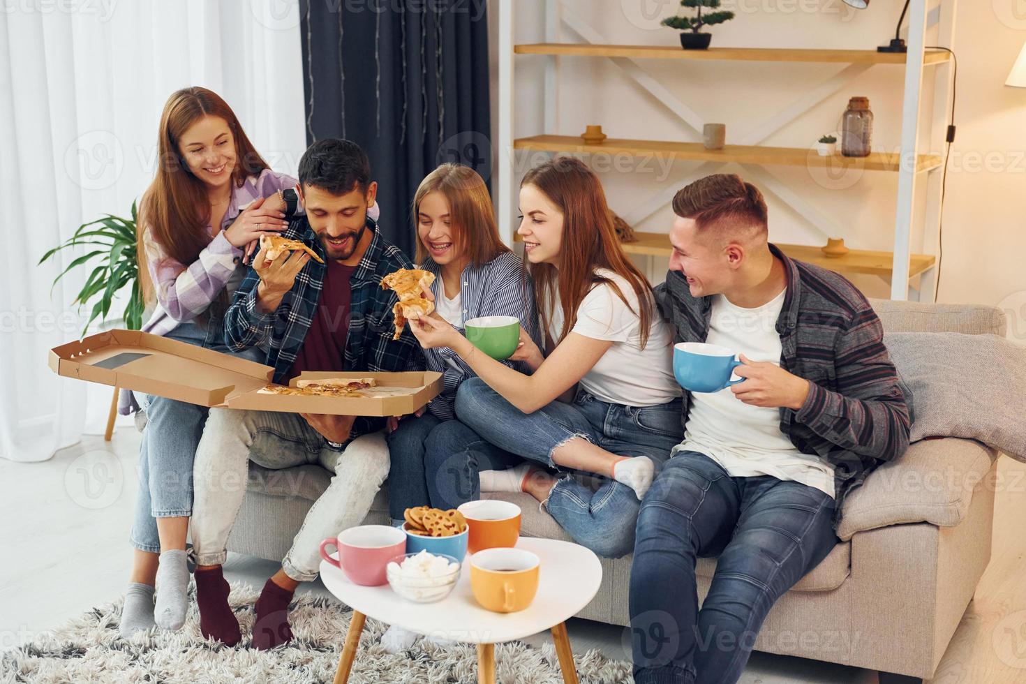 comiendo comida y bebiendo té. grupo de amigos tienen una fiesta en el interior juntos foto