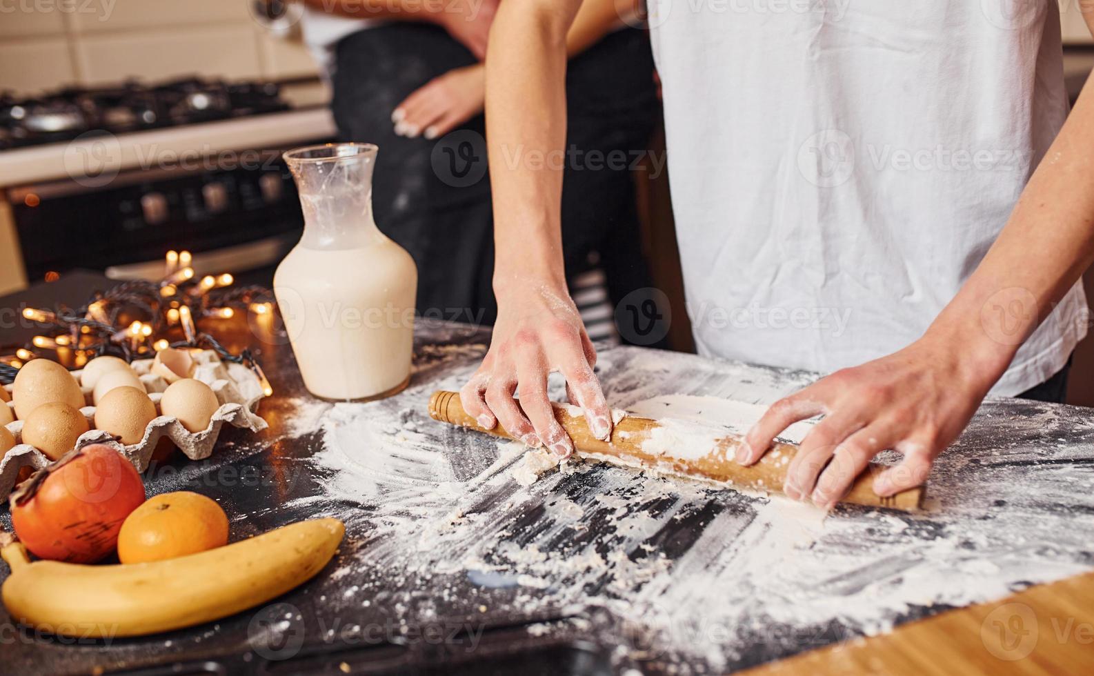 Wife with husband embracing each other. Their son preparing food photo