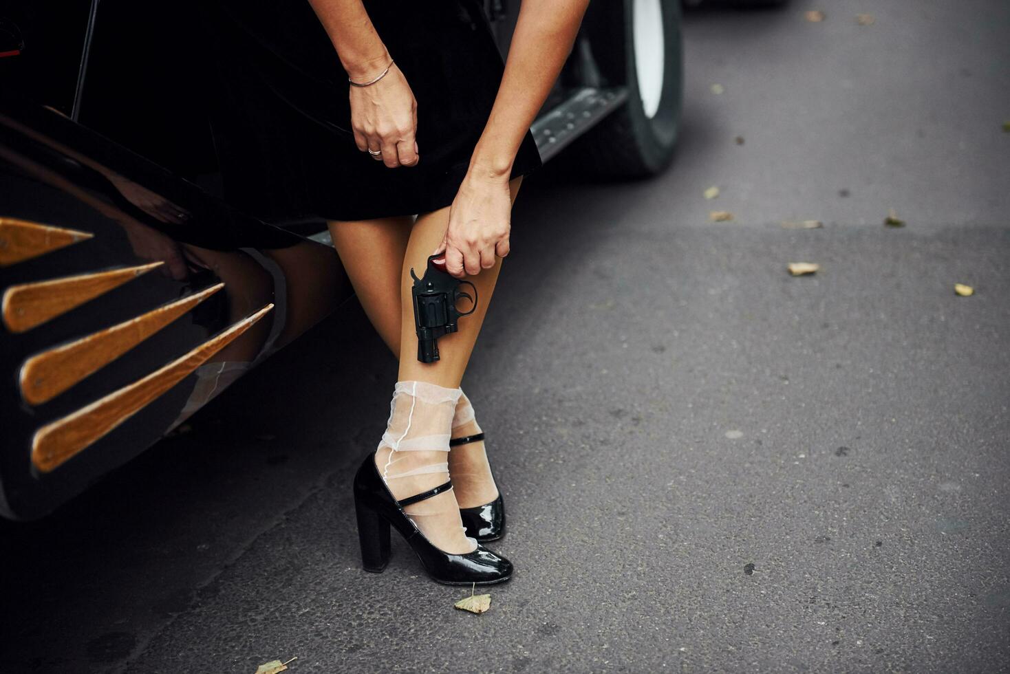 vista de cerca de las piernas de la mujer cerca del coche antiguo. con pistola en mano foto