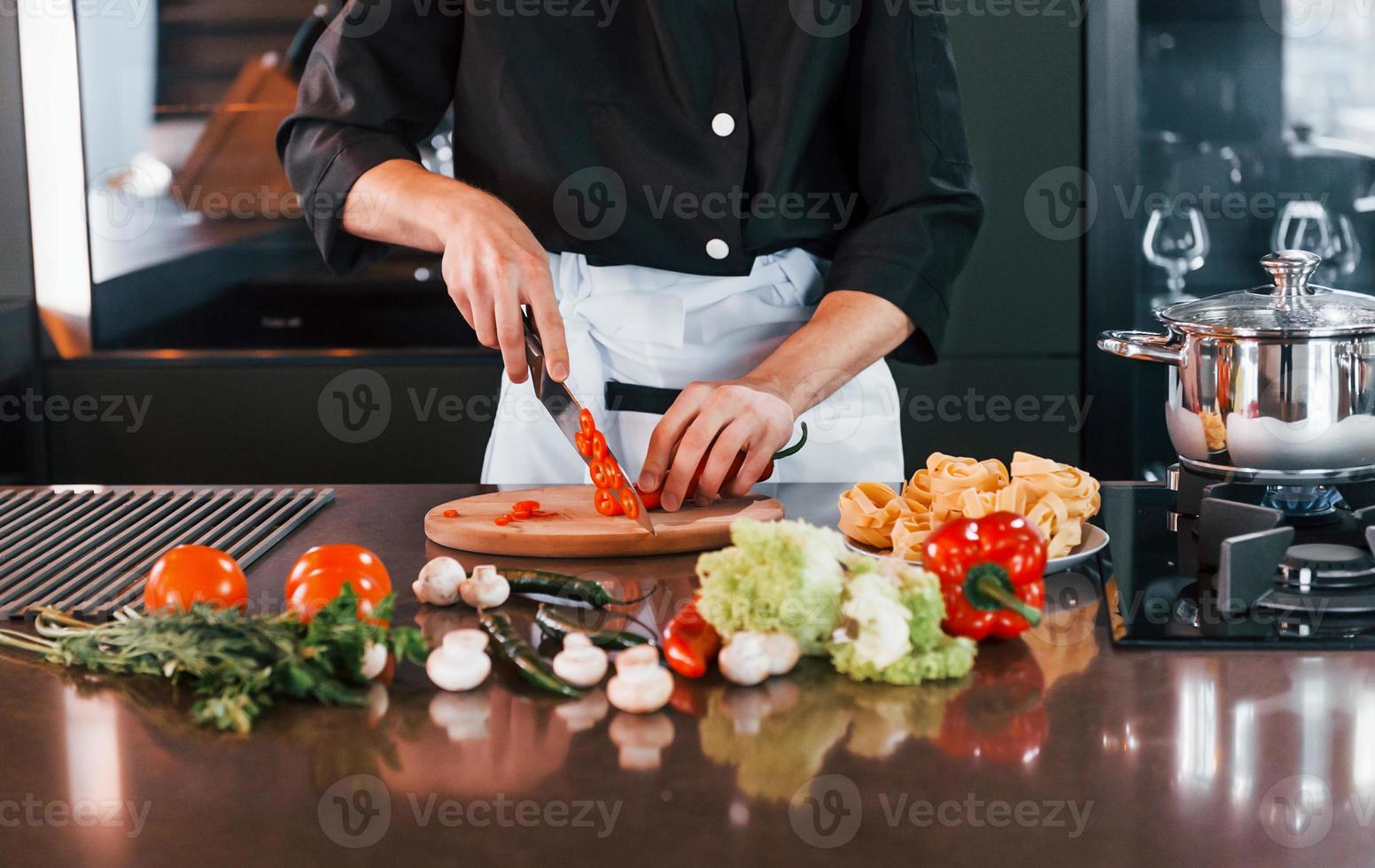 Close up view of professional young chef cook in uniform that working on the kitchen photo