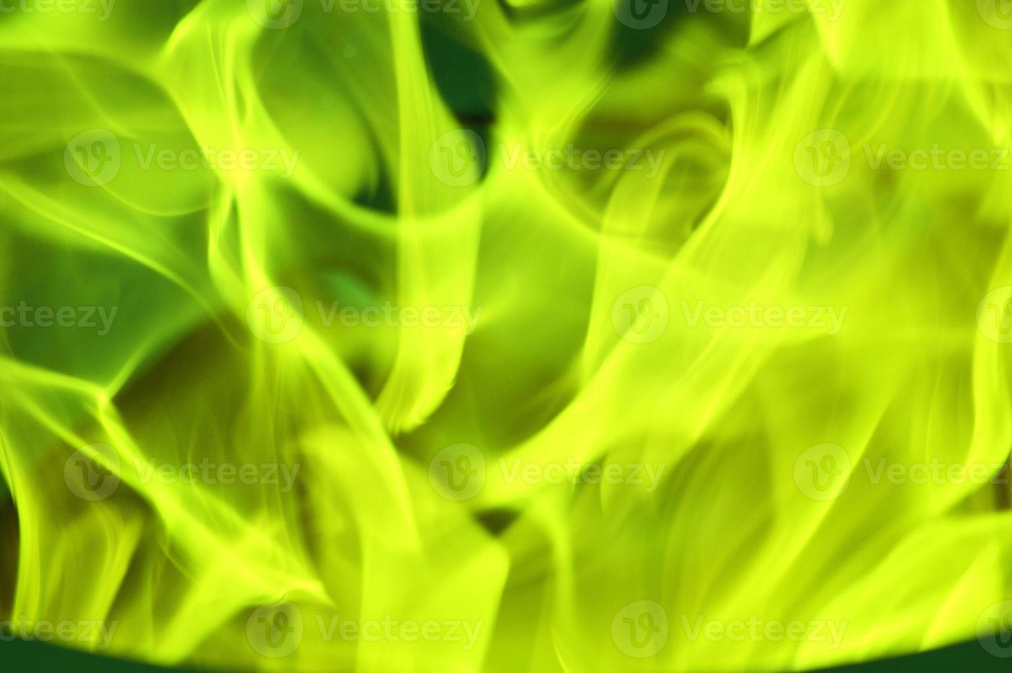 Green and yellow bright tongues of flame, glare, smoke on a dark background. Abstract color background. photo