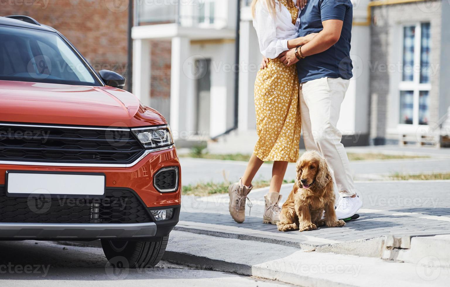 Particle view of lovely couple that have a walk together with dog outdoors near the car photo