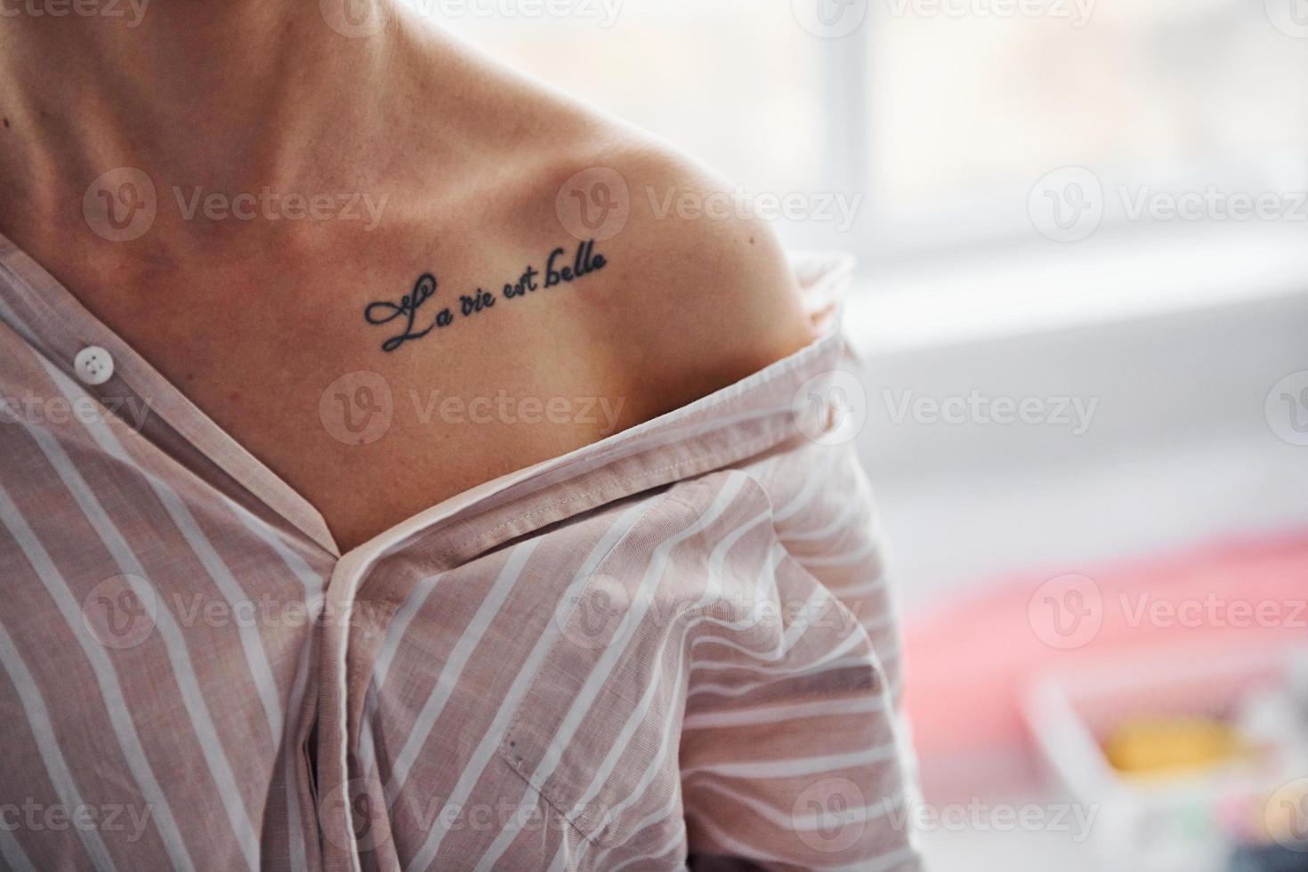 Close up view of tattoo of woman in shirt with stripes indoors photo