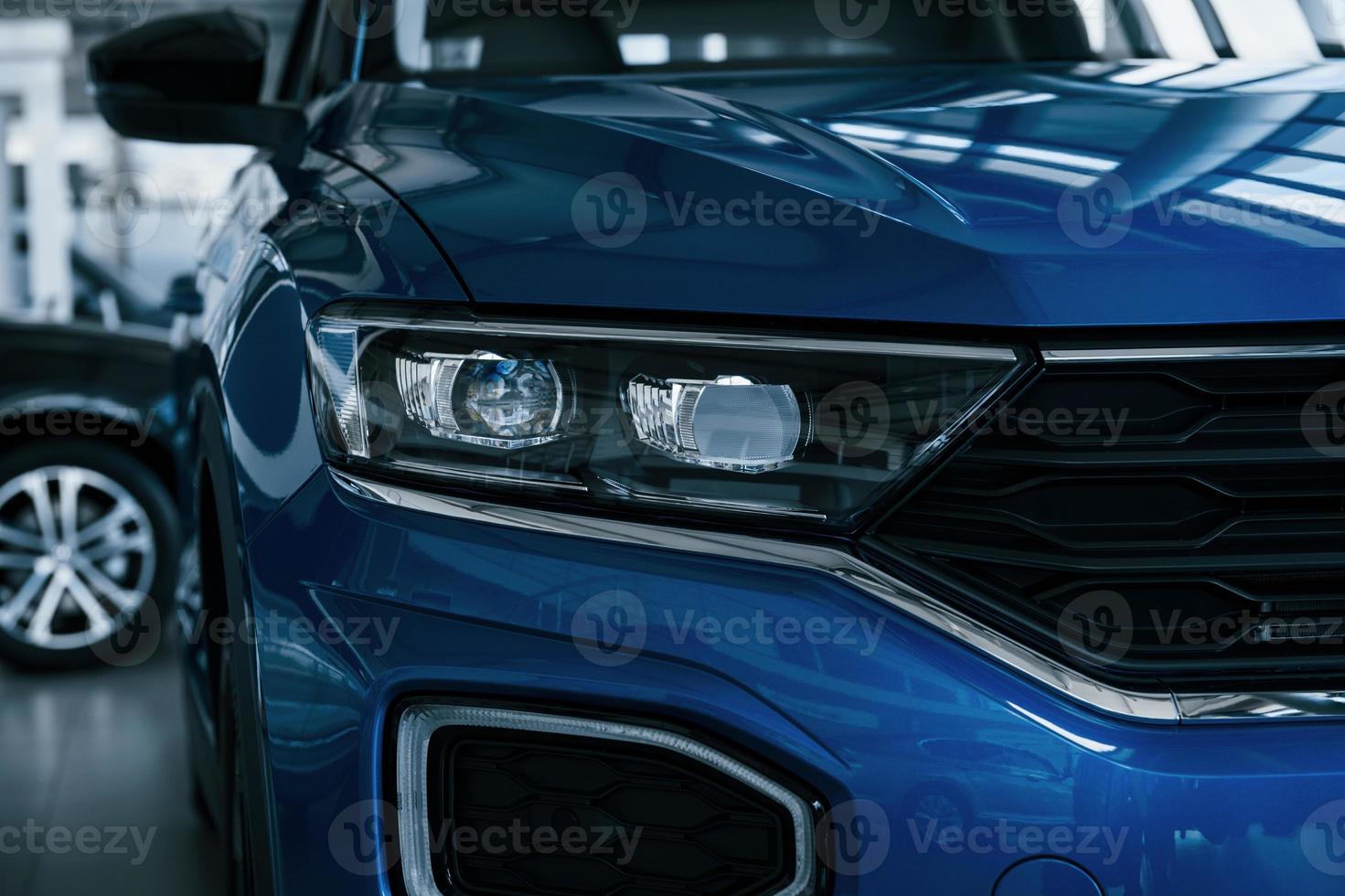 Front part of brand new modern blue car. Parked at showroom. Reflection in the headlights photo