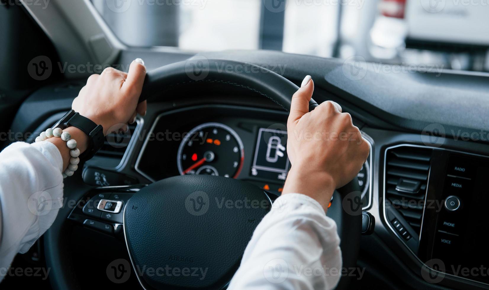 vista de partículas de la mujer que prueba un coche nuevo y moderno en la sala de exposición foto