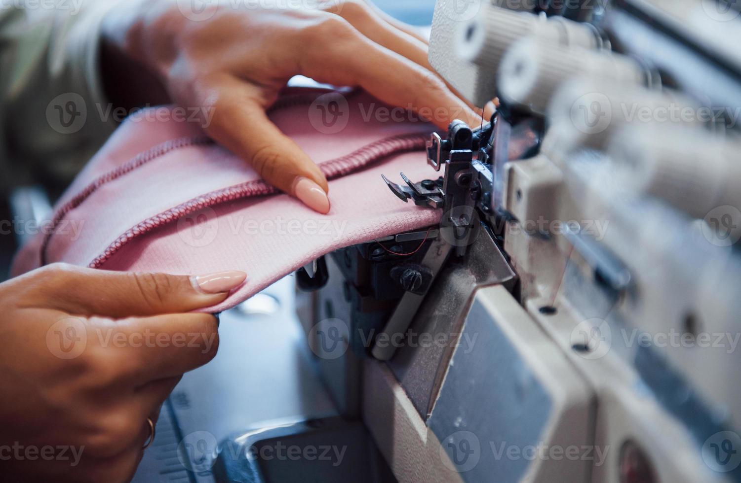 Detailed view of dressmaker woman sews clothes on sewing machine in factory photo