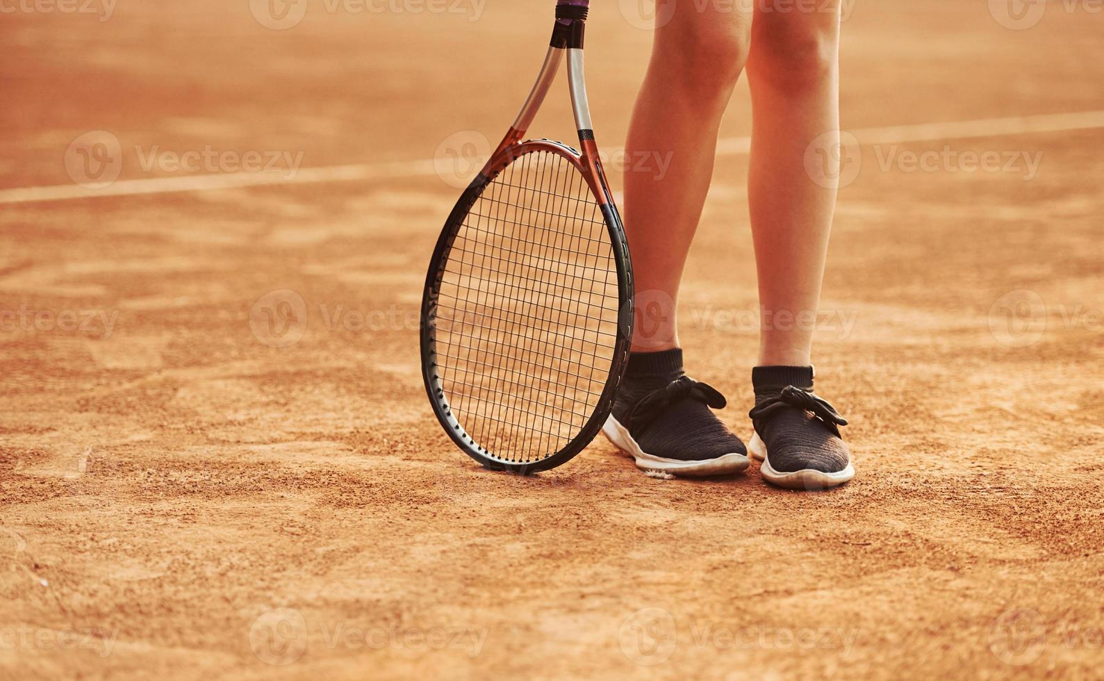 Legs and racket of female player that stands in the court at daytime photo