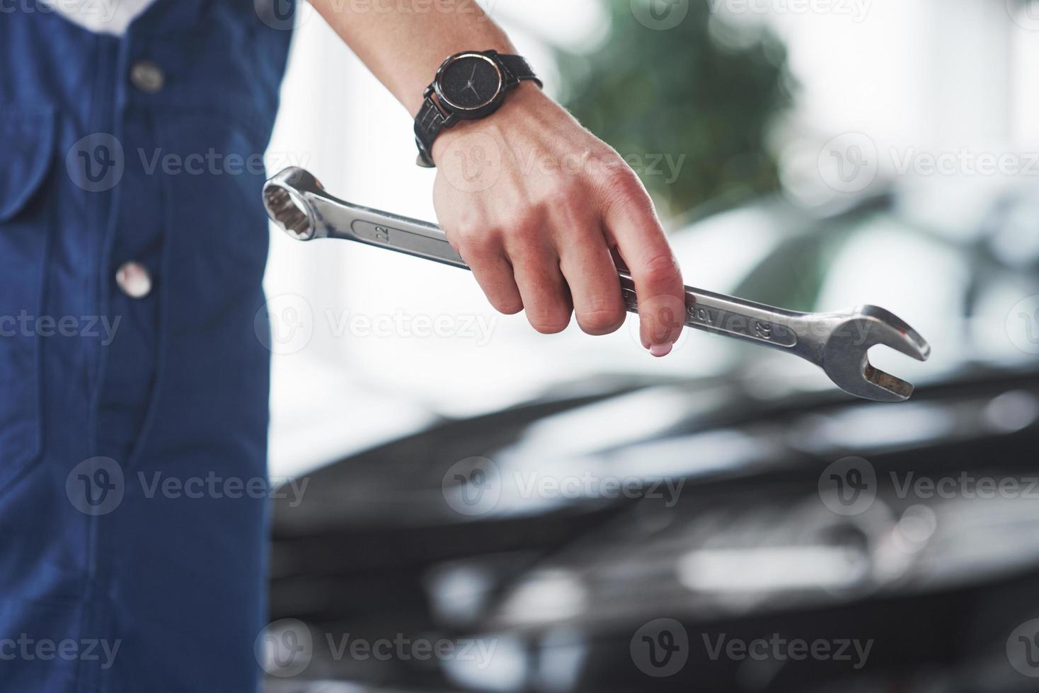 Holding wrench. Woman repairer is on her work. Indoors at car shop photo