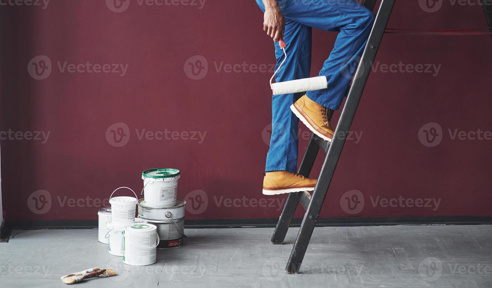 Walking up the ladder. Young african american worker in the blue uniform have some job photo