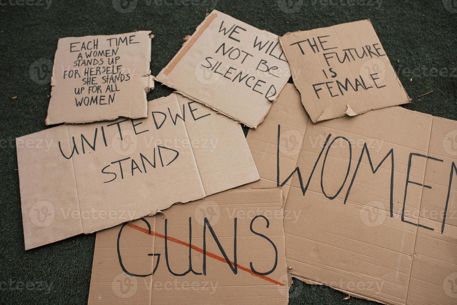 Group of banners with different feminist quotes lying on the ground photo
