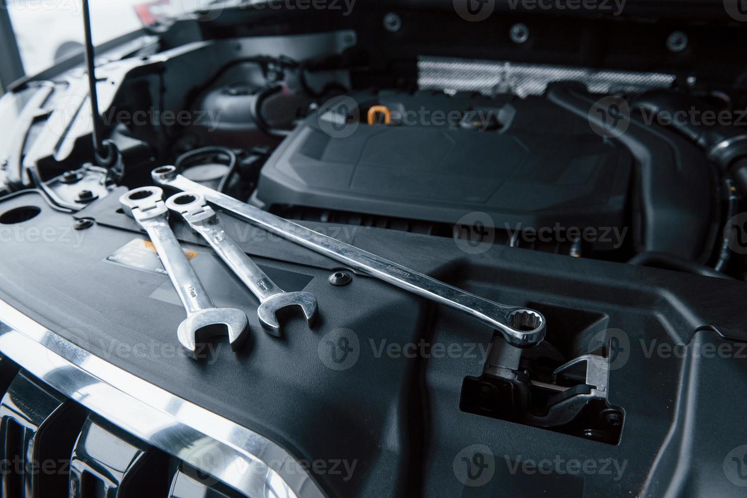 Group of objects. Repair tools lying down on the engine of automobile under the hood photo