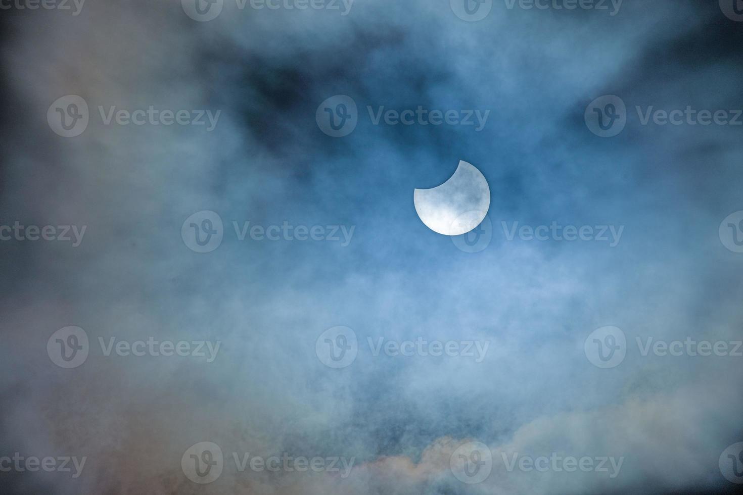 Image of a partial solar eclipse through veil clouds photo