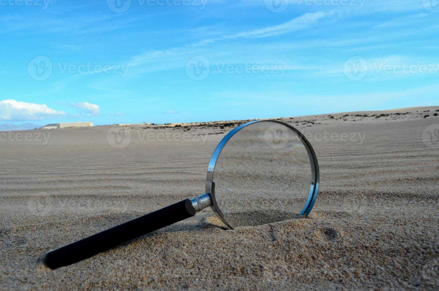 Magnifier glass on the sand photo