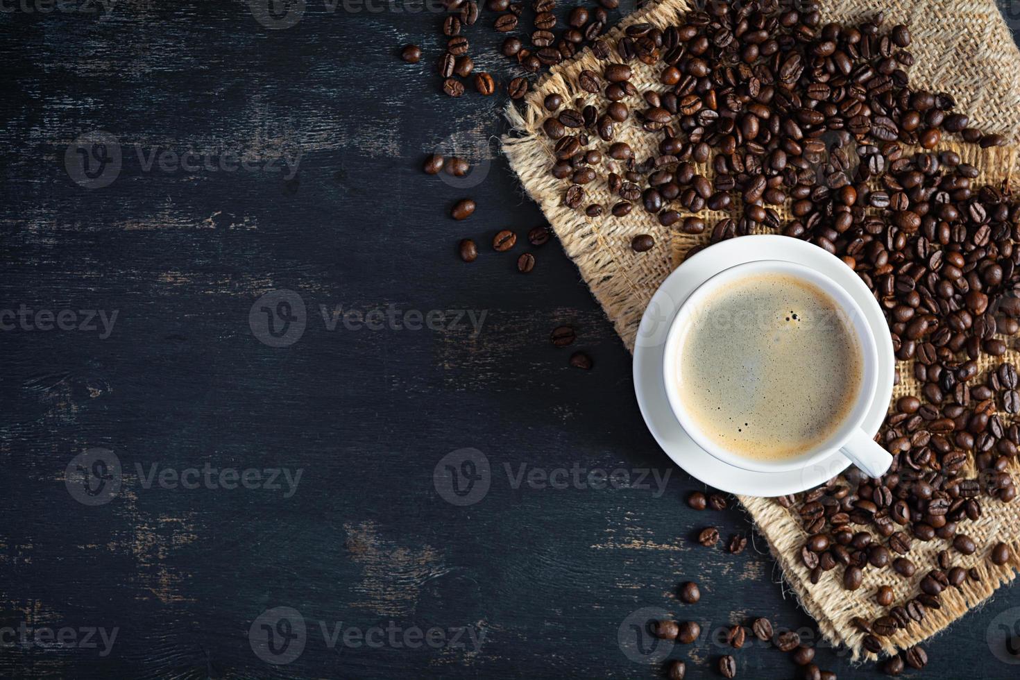 Cup of coffee with coffee beans on dark background. Mug of hot drink coffee photo