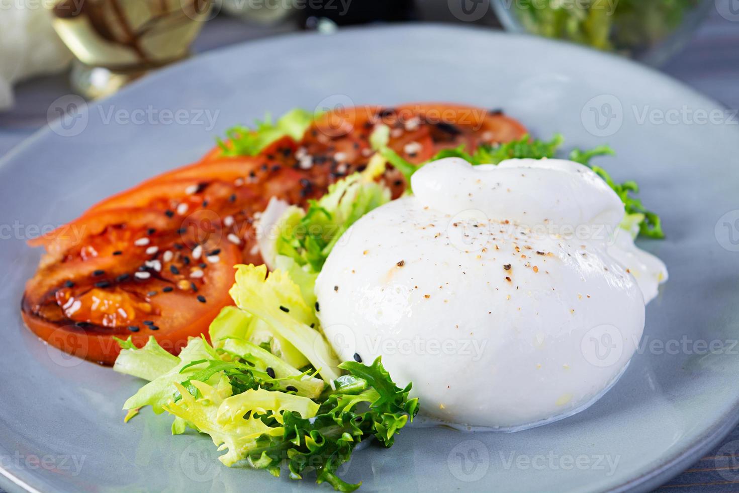 Fresh salad with burrata, lettuce and tomatoes. Delicious Italian cheese made from mozzarella and cream photo