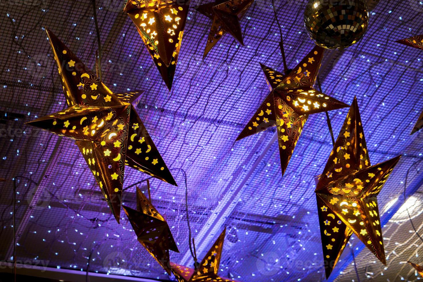 Decorated lighting golden stars and blue lights of decorated lighting  hanged on ceiling in the room for ready on the Christmas night party. photo