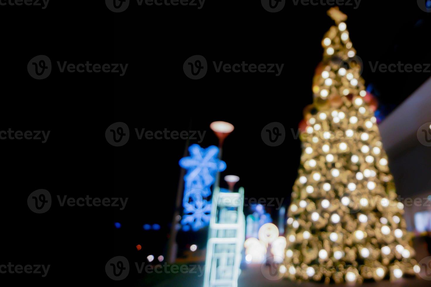 Blurred and bokeh view of Christmas tree and decorate led lighting front of shopping mall on Christmas night in urban city. photo