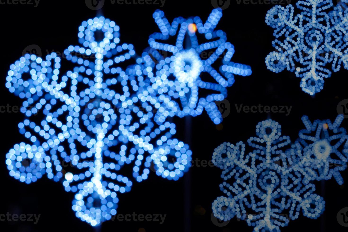 Blurred and bokeh decorated led of Christmas blue lighting in snowflake shape on night time and black background. photo