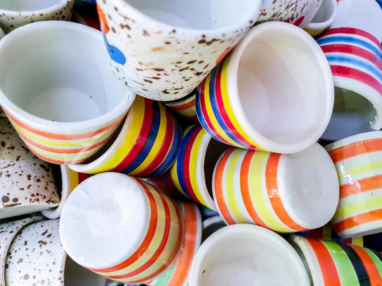 El primer plano y el montón de recortes de una taza de café de cerámica a rayas de colores y esparcidos se ajustan al fondo de la pantalla y al papel tapiz. foto