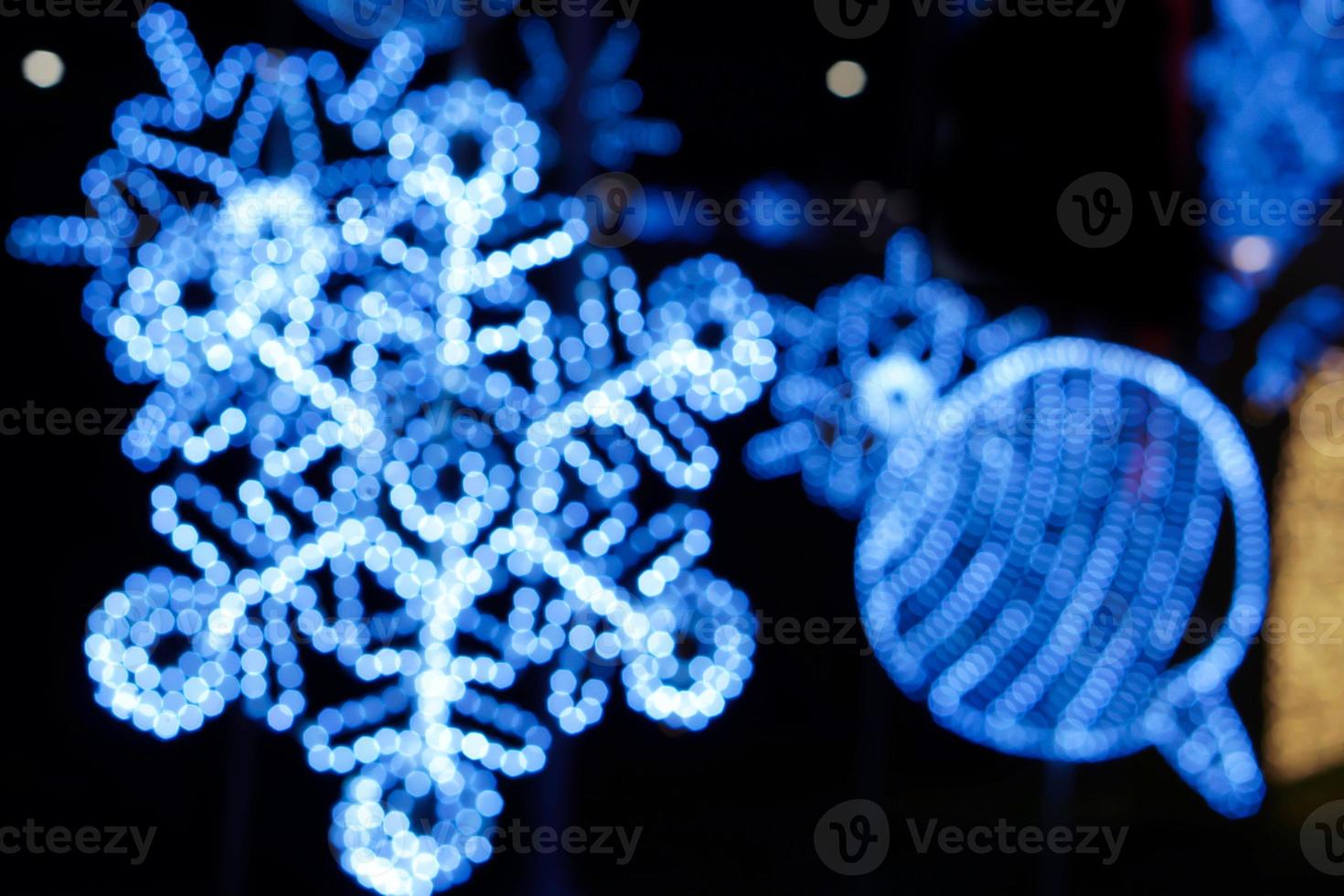 Blurred and bokeh decorated led of Christmas blue lighting in snowflake shape on night time and blurry background. photo