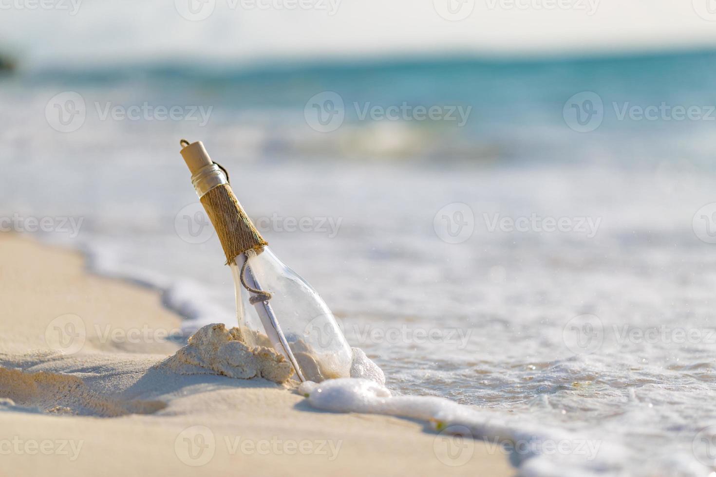 mensaje en la botella arrastrada a tierra contra la puesta del sol. botella con un mensaje foto