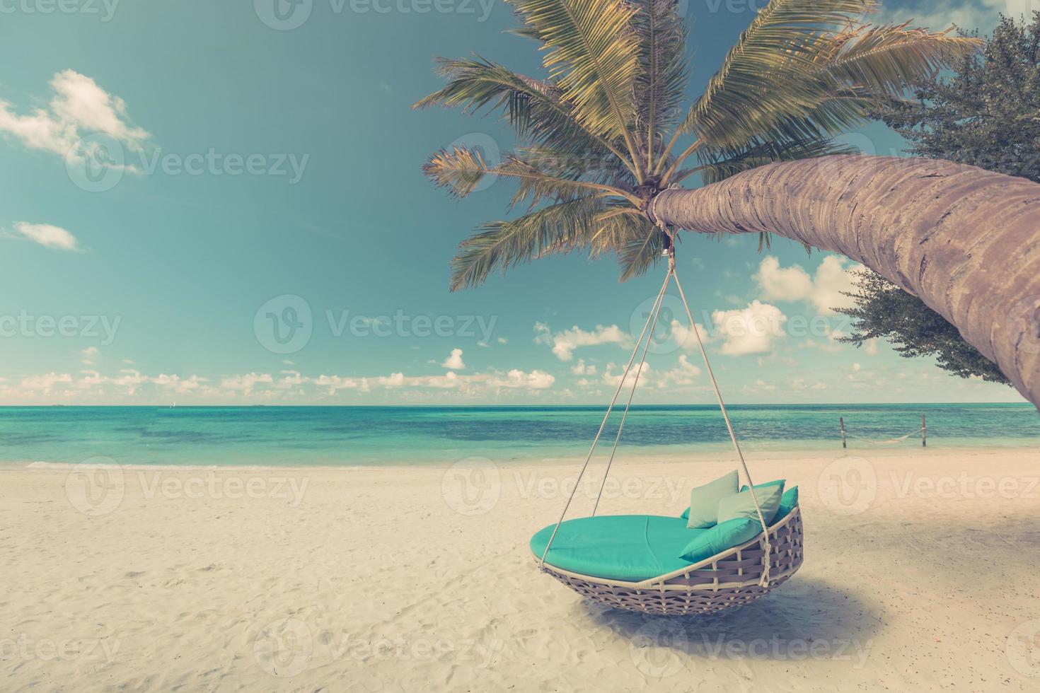 Tropical beach background as summer landscape with beach swing or hammock over white sand and calm sea for beach banner. Sunset beach scene vacation and summer holiday concept. Soft up color process photo